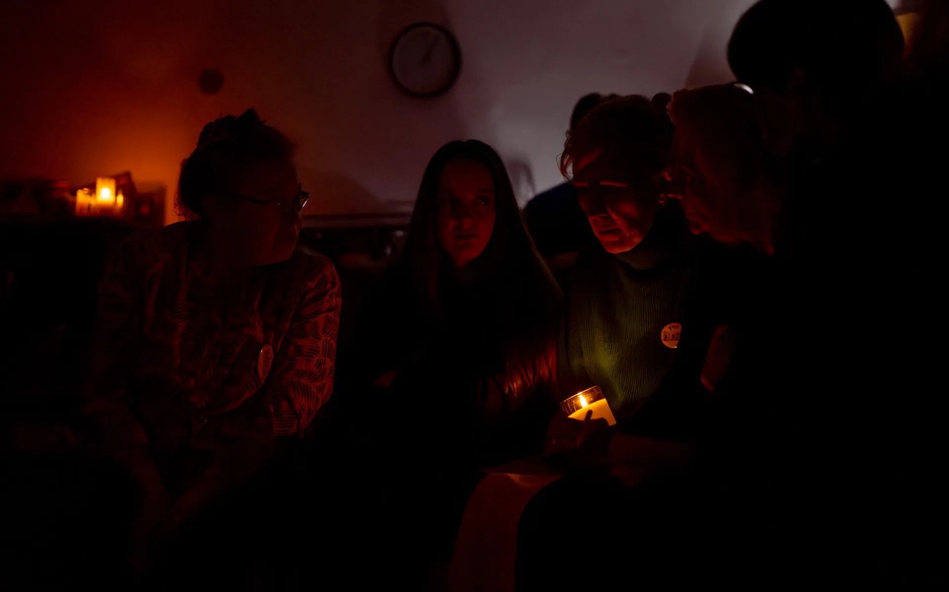 Účastníci kurzu BLACKOUT sedí ve tmě kolem jediné svíčky