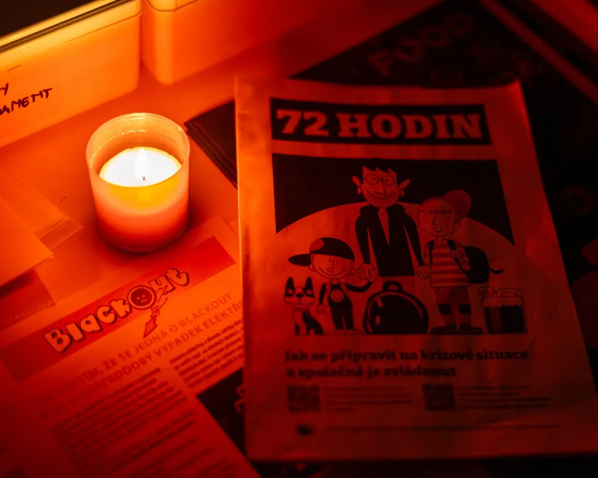 Svíčka a příručka 72 hodin na stole v zatemněné místnosti