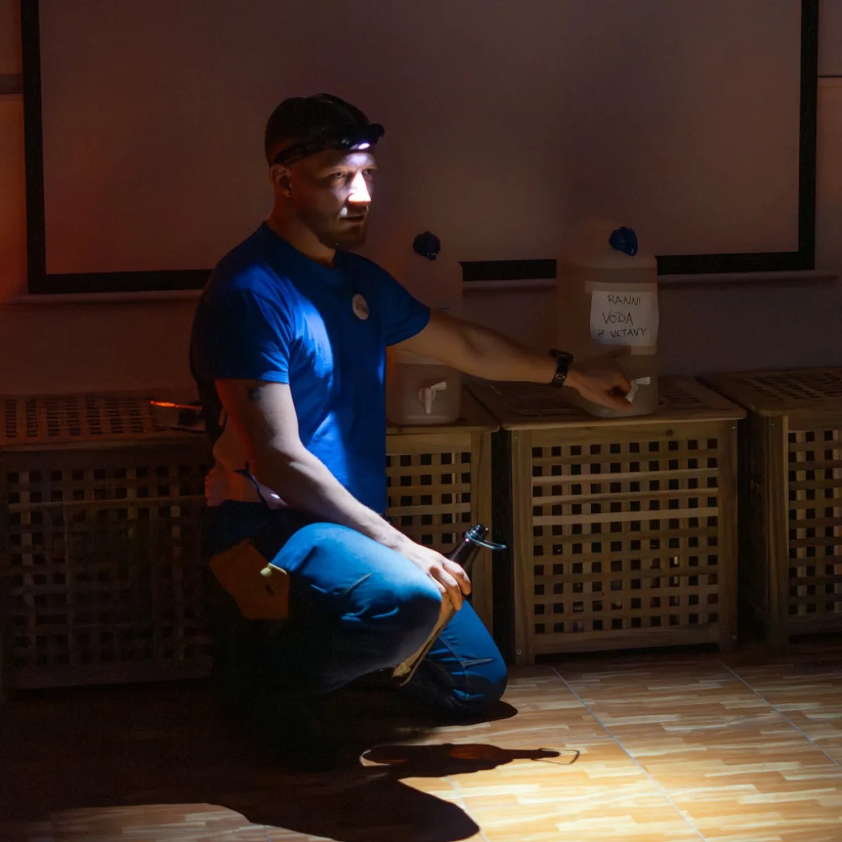 Účastník s čelovkou u nouzové zásoby pitné vody
